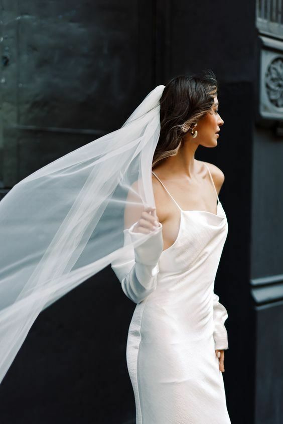 Braut in einem Slipdress aus Seide mit wehendem Schleier