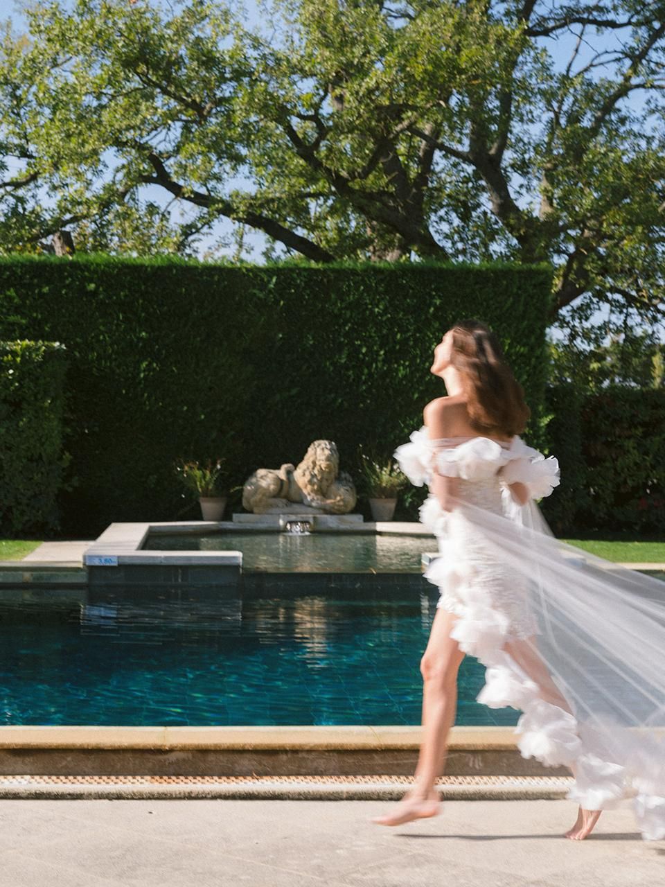 Sposa in abito a balze che passeggia lungo la piscina, Château de Tourreau