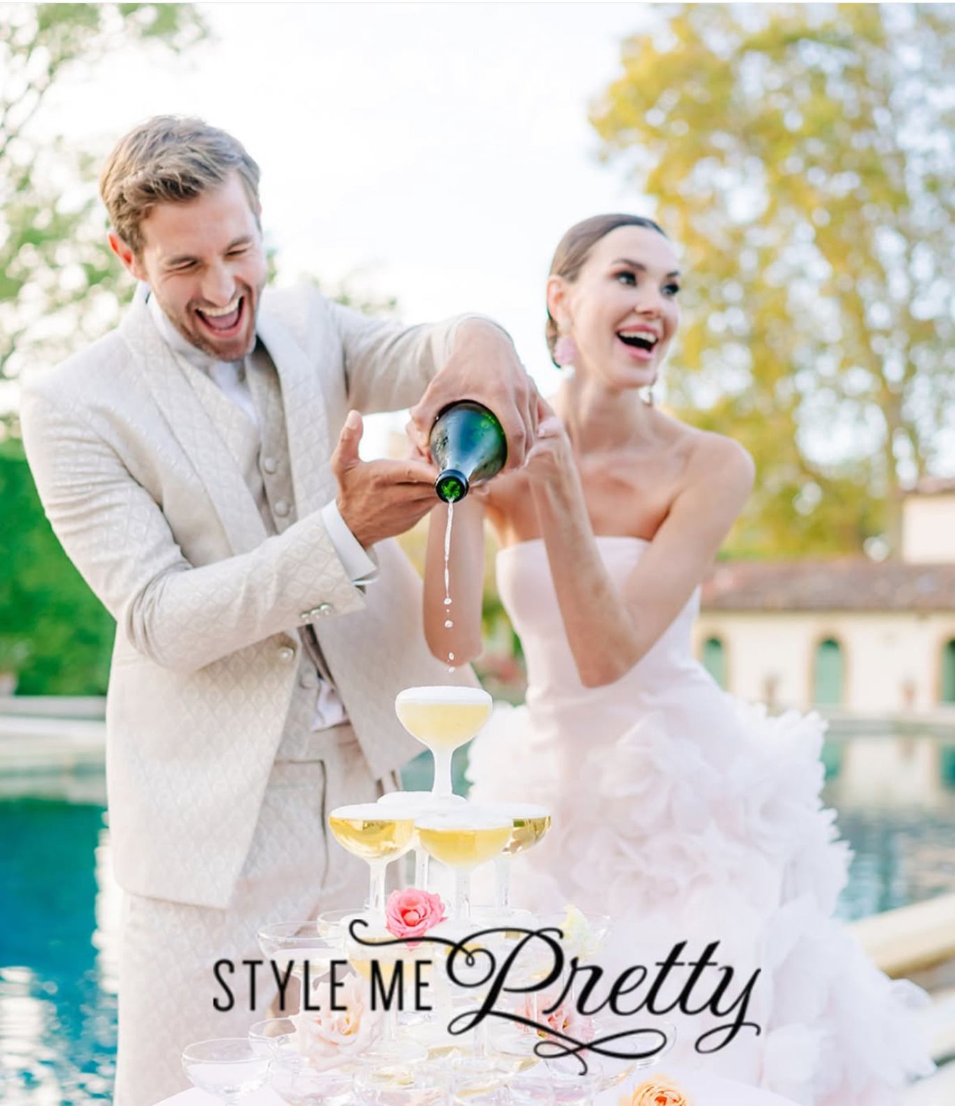 Pareja sirviendo champán junto a una piscina con el logo de Style Me Pretty