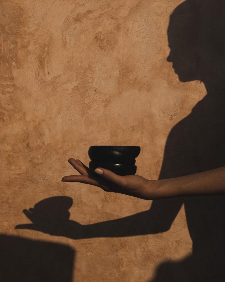 Schatten einer Hand mit einer Schale auf einer Terrakottawand