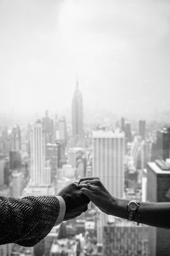 Foto en blanco y negro de unas manos tendidas hacia el Empire State Building
