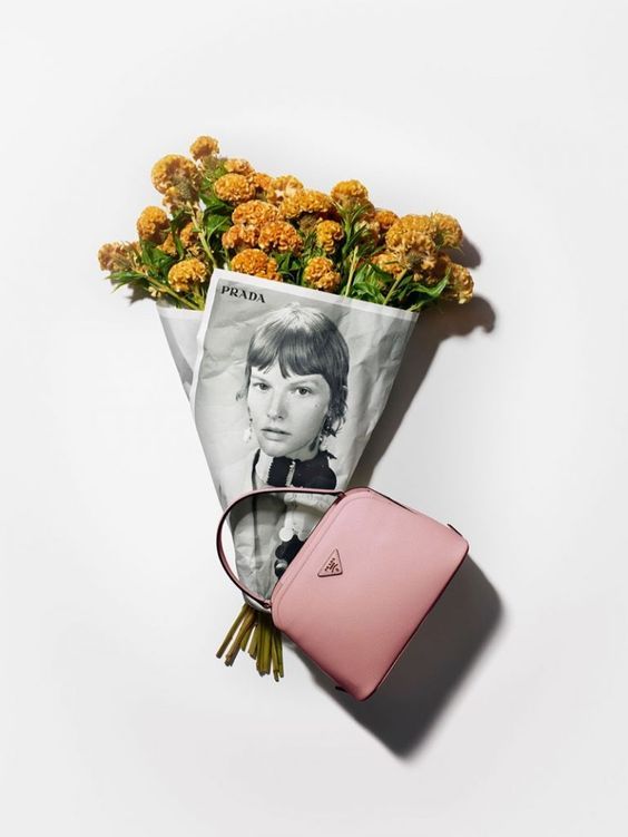 Flores naranjas envueltas en papel de periódico con un bolso rosa