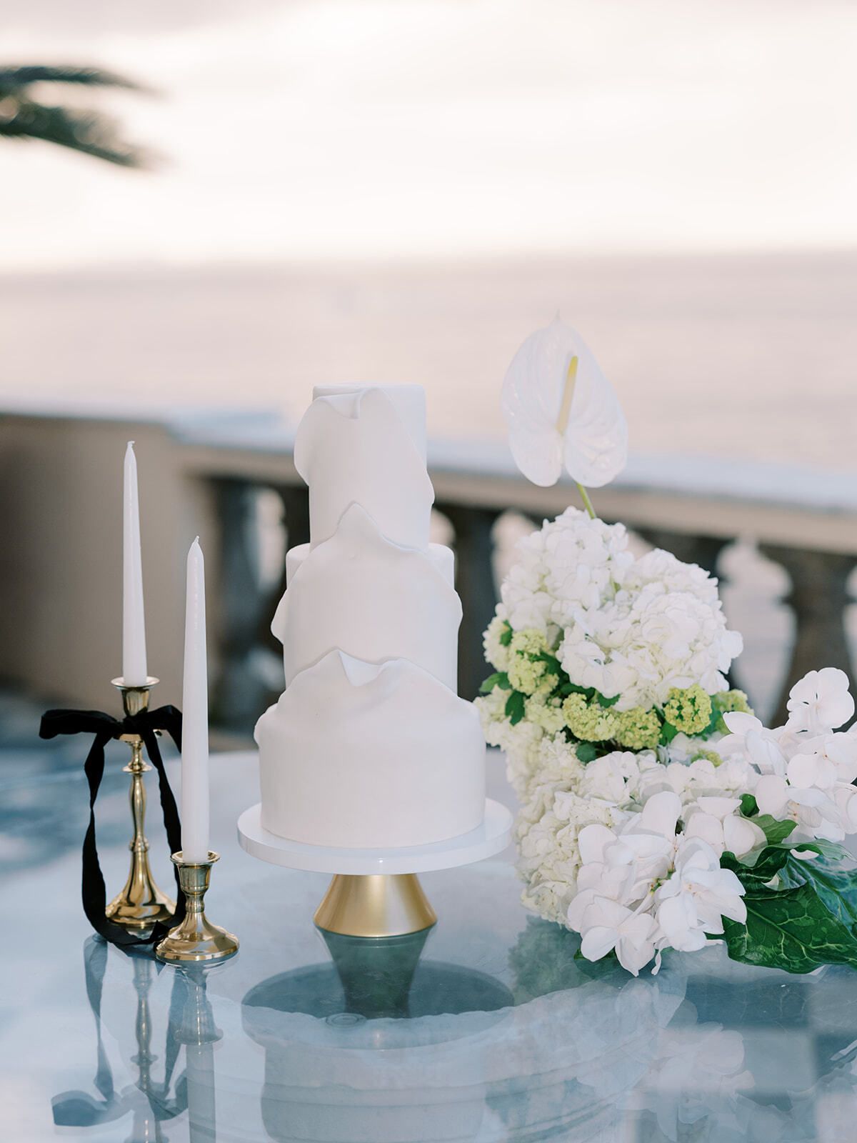 Torta nuziale bianca con candele e fiori bianchi vista mare