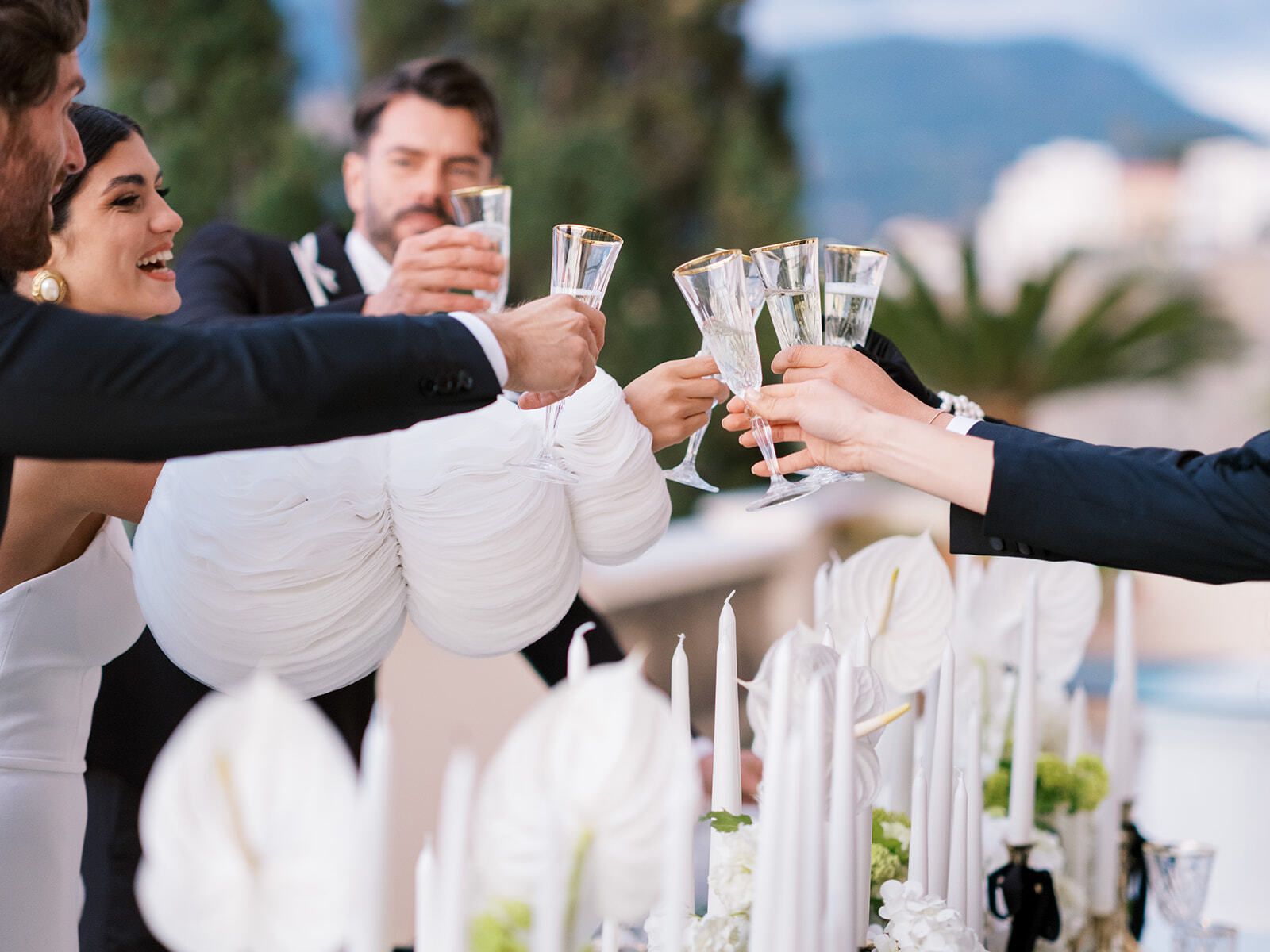 Invités trinquant au champagne à une table aux chandelles sur la terrasse d’une villa