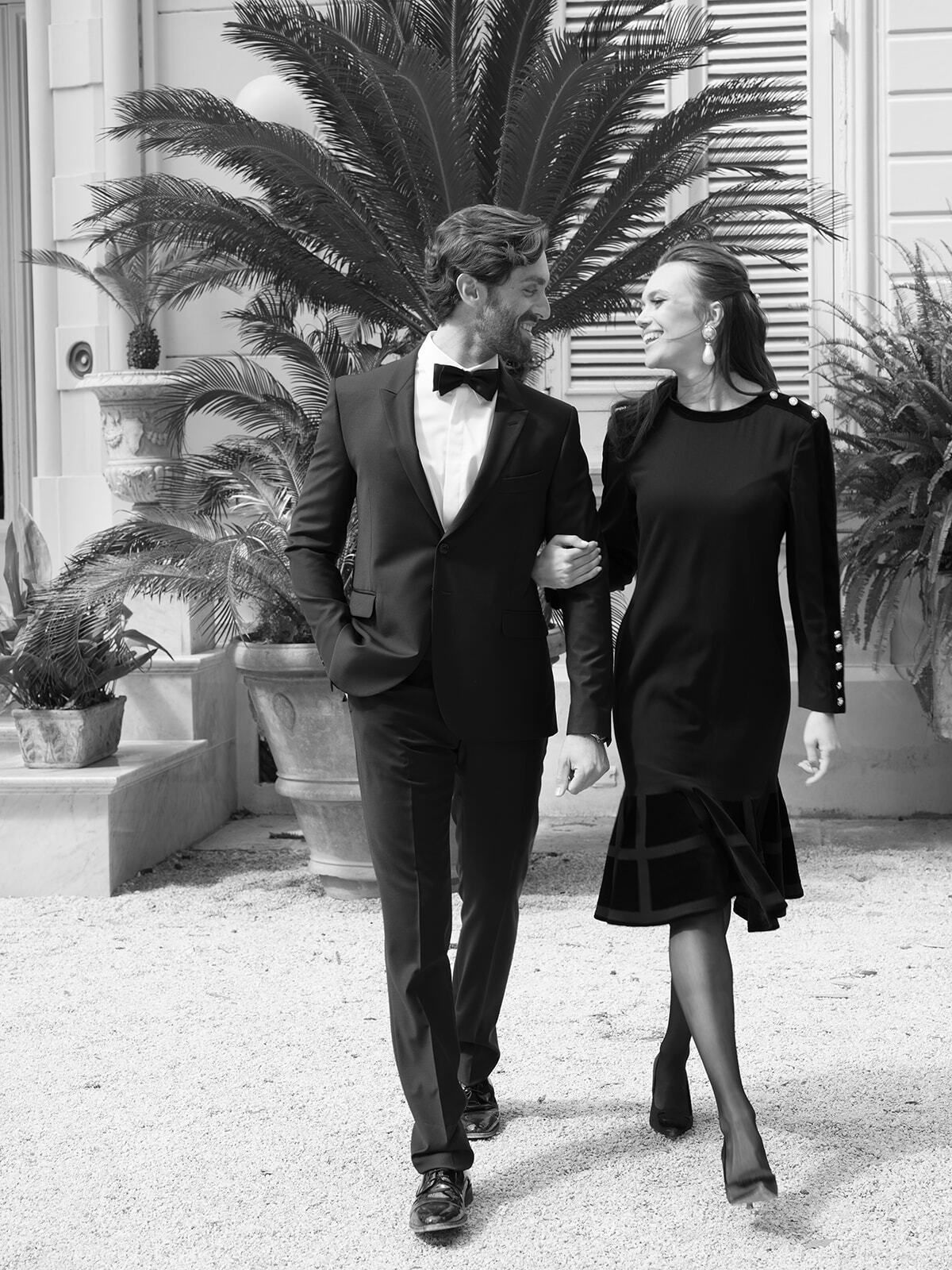 Schwarz-Weiß-Foto: Bräutigam und Gast spazieren durch den Villengarten