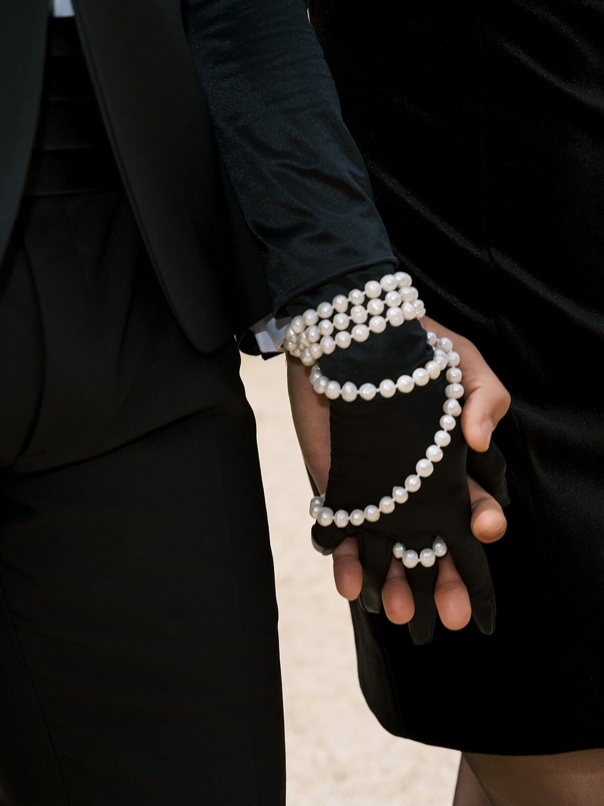 Bracciali di perle su un guanto di pizzo nero, dettaglio di un’invitata