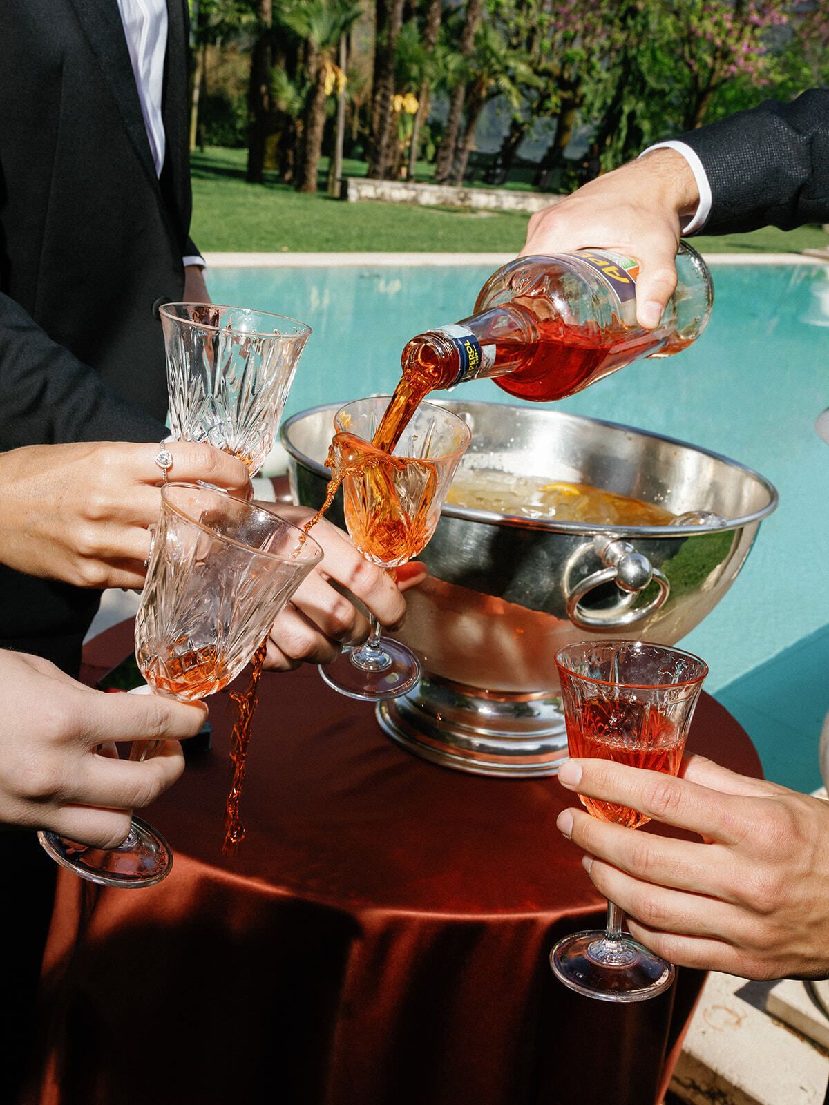 Champagner wird am Pool aus einer Silberschale in Gläser gegossen