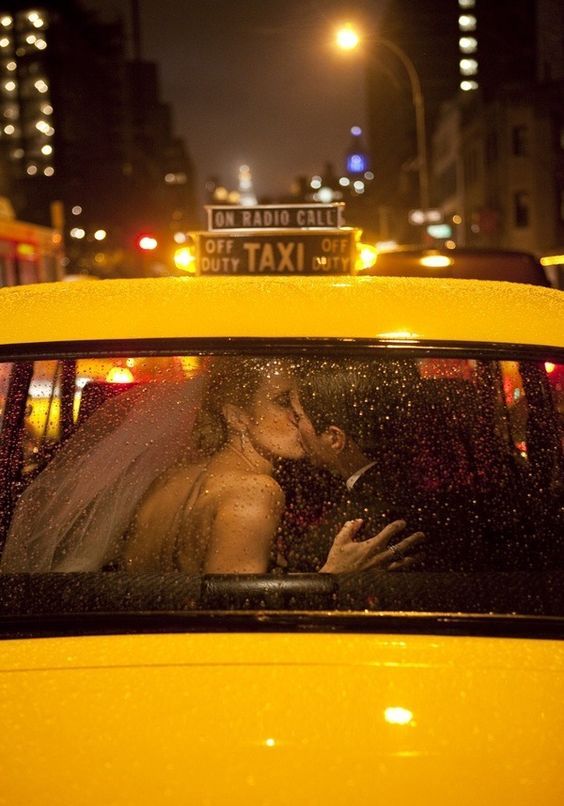 Pareja besándose en el asiento trasero de un taxi amarillo de Nueva York de noche