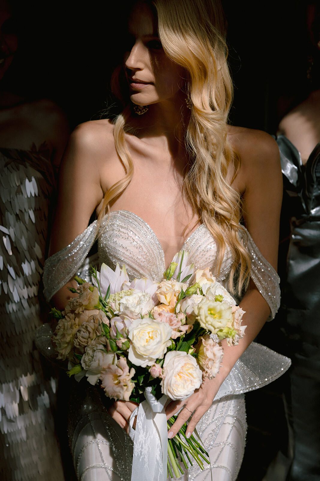 Bride in a pearl-embellished gown holding a pastel bouquet