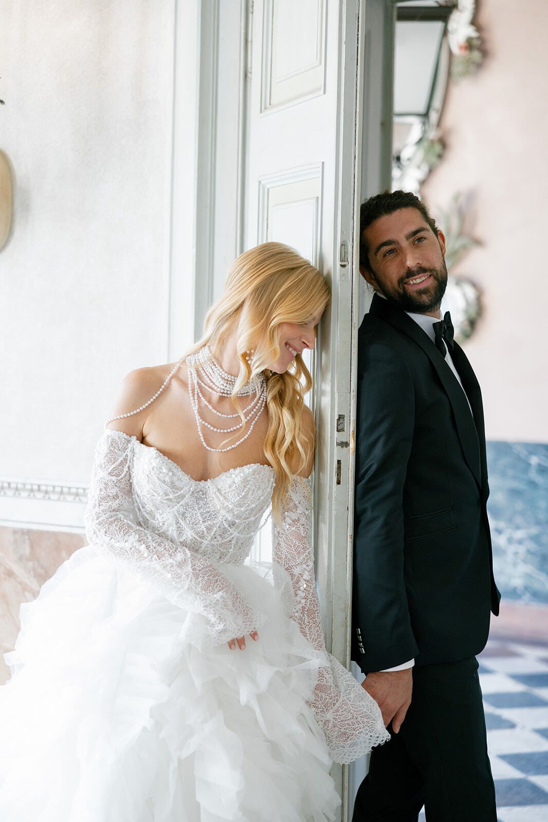 Bride in lace peeking at the groom through a doorway