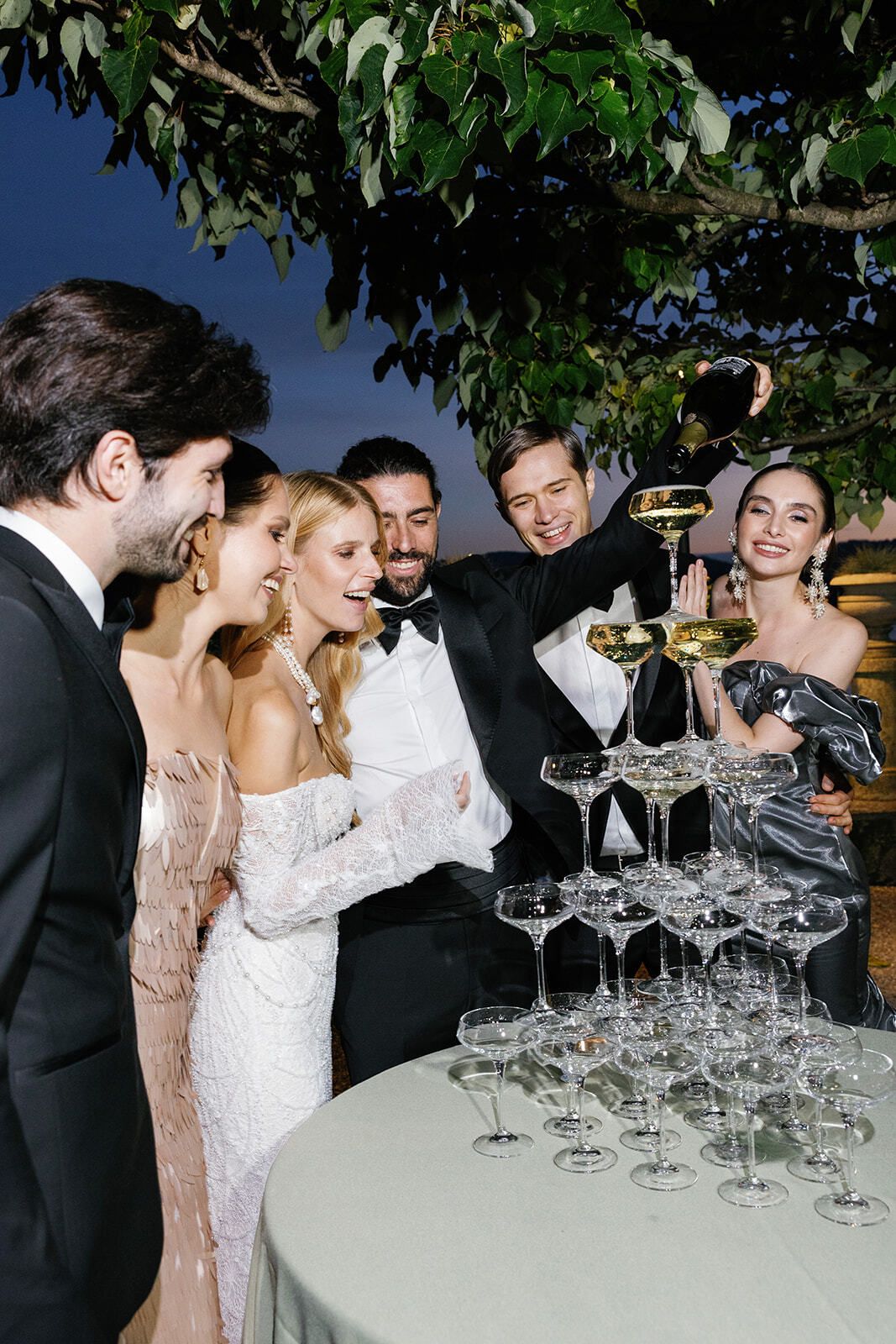 Guests laughing around a champagne tower at night