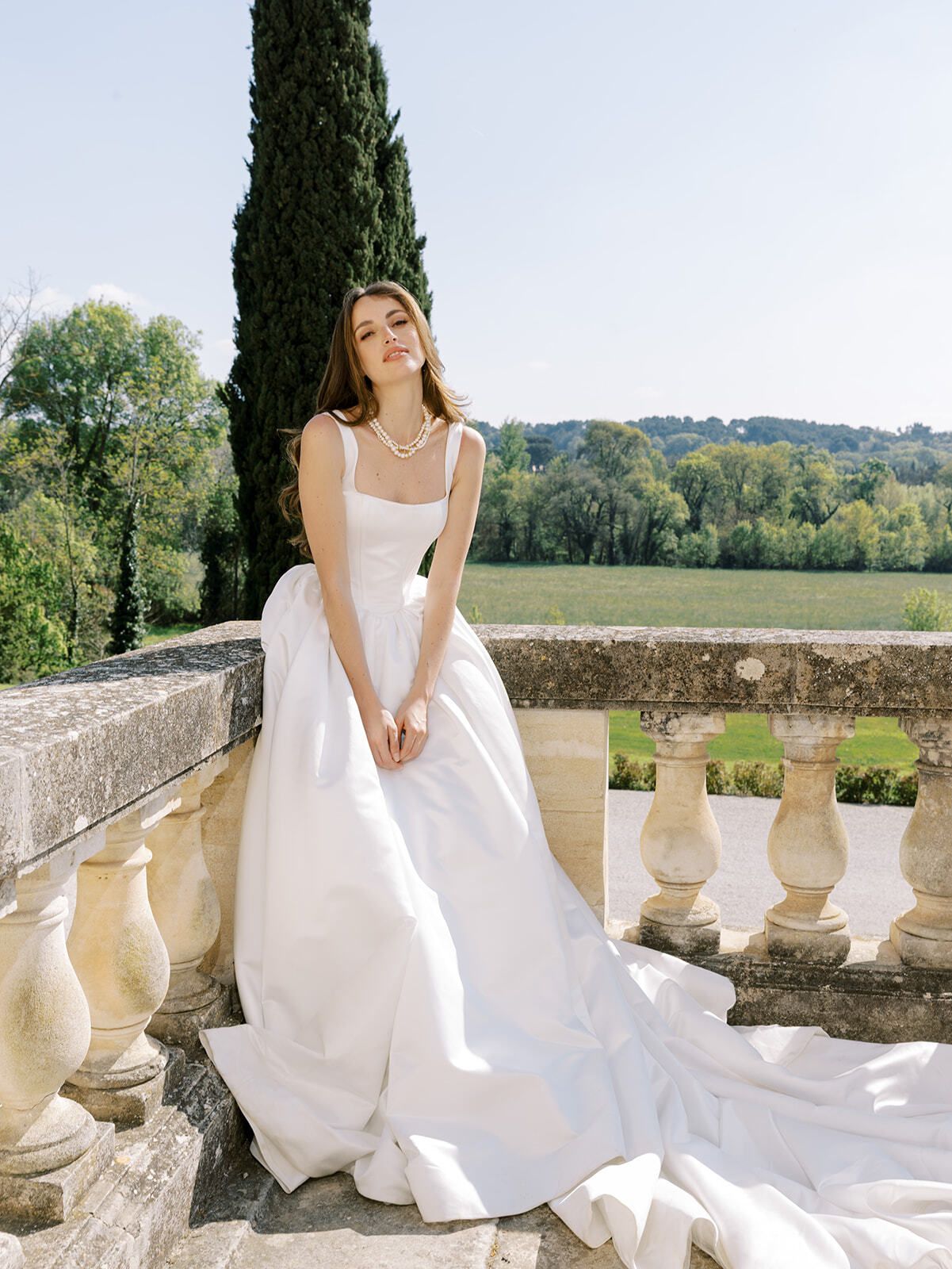 Braut sitzt auf einer Steinbalustrade mit Blick über die Provence
