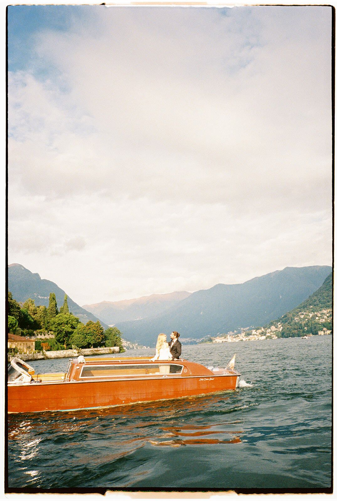Couple sur un bateau en bois orange sur le lac de Côme