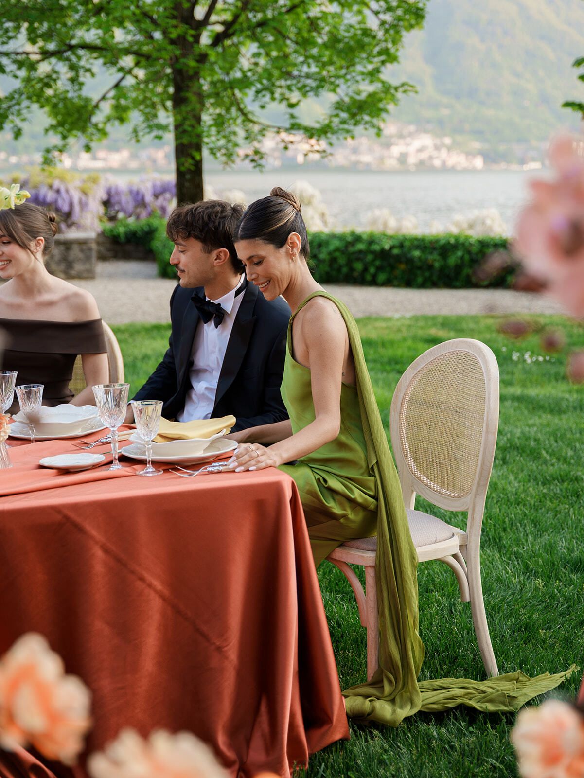 Gäste an einer terrakottafarben gedeckten Tafel im Garten der Villa
