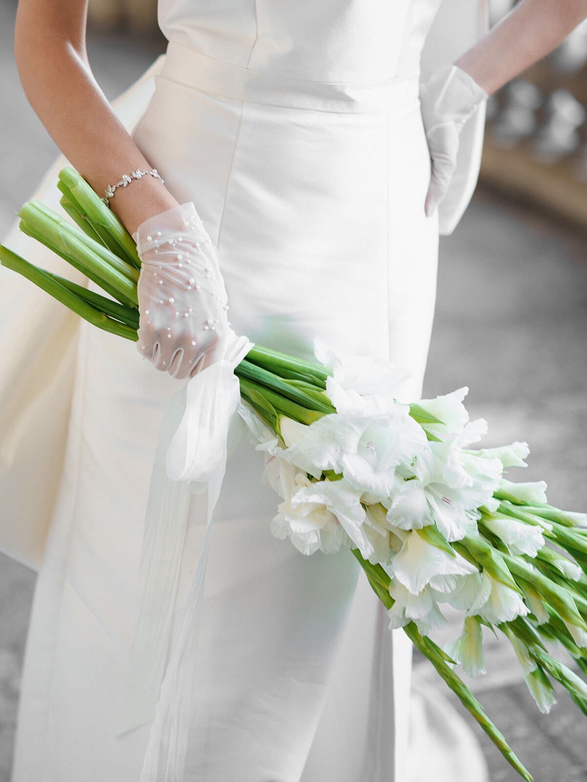 Braut mit Spitzenhandschuhen hält weiße Calla-Lilien