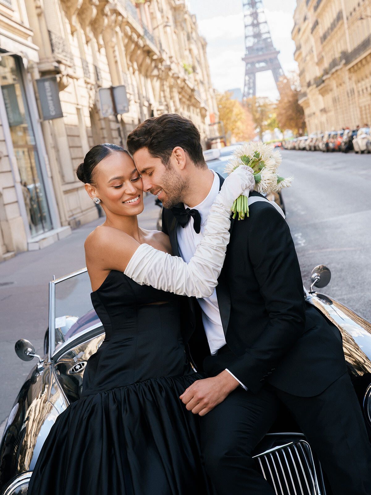 Paar umarmt sich auf einem Oldtimer in einer Haussmann-Straße, Paris