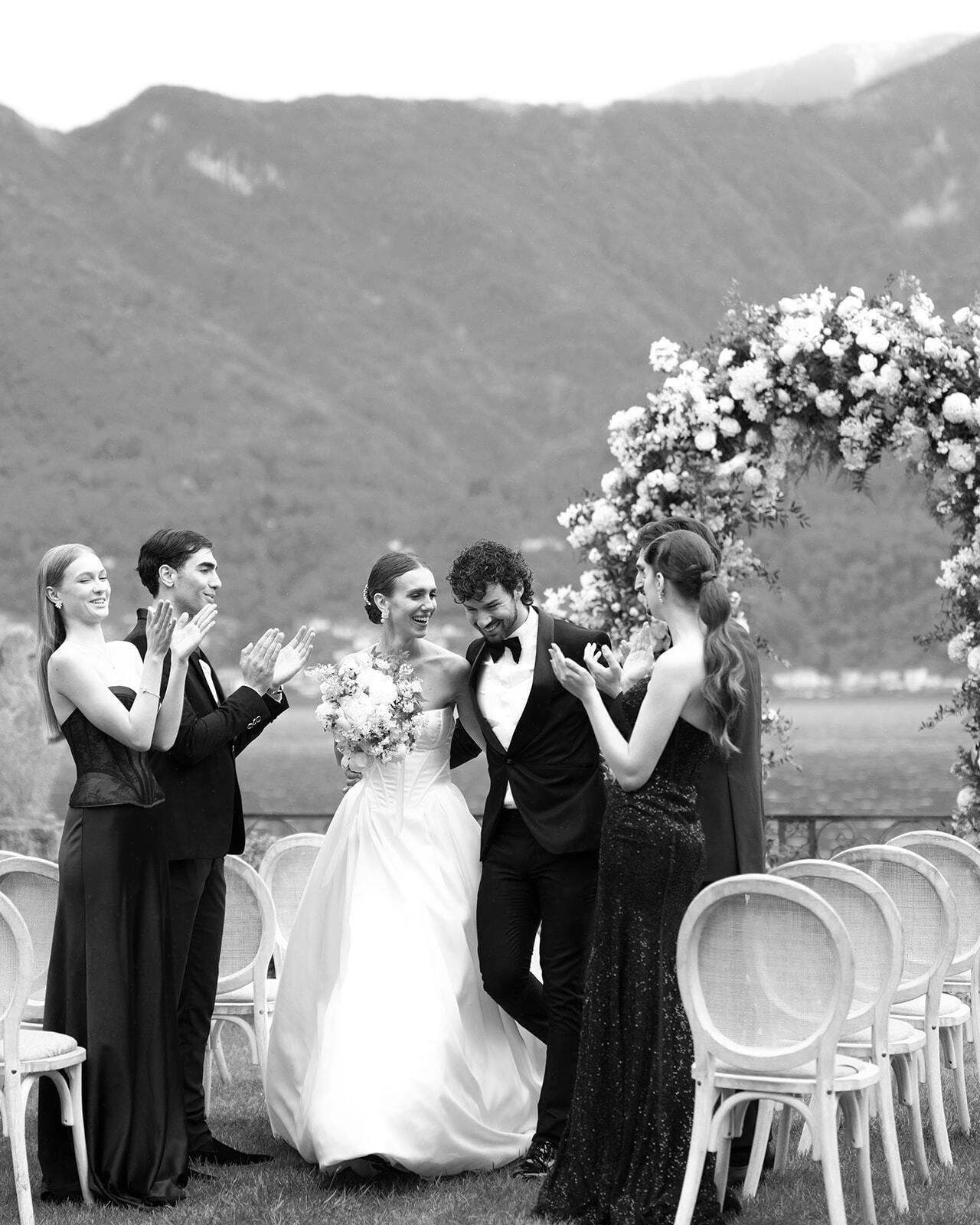 Schwarz-Weiß-Foto der Hochzeitsgesellschaft beim Anstoßen am See