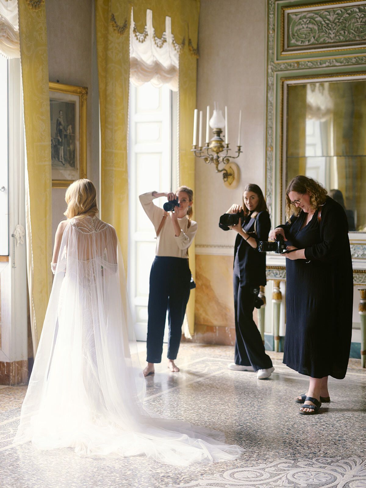 Fotograf:innen fotografieren eine Braut in einem Salon einer Villa während eines Workshops