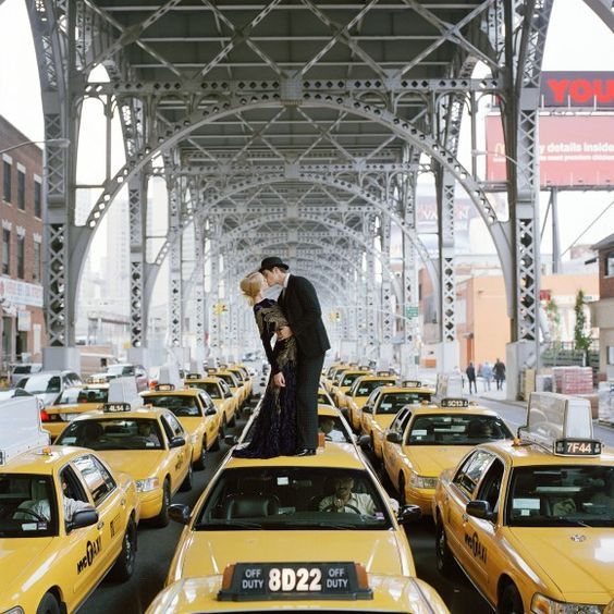 Pareja besándose sobre un taxi amarillo bajo un viaducto de acero en Nueva York
