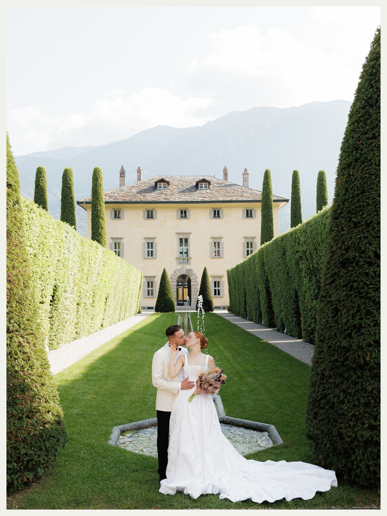 Bride and groom kissing in the cypress avenue at Villa Balbiano