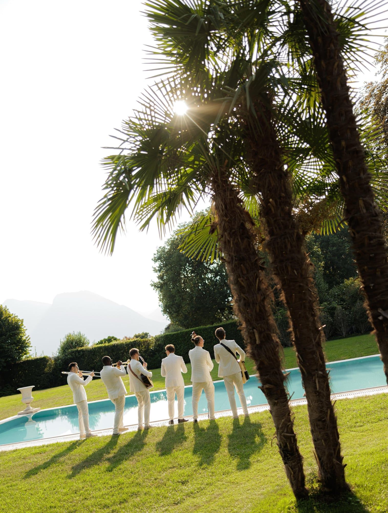 Band in white suits by the pool under palm trees at Villa Balbiano