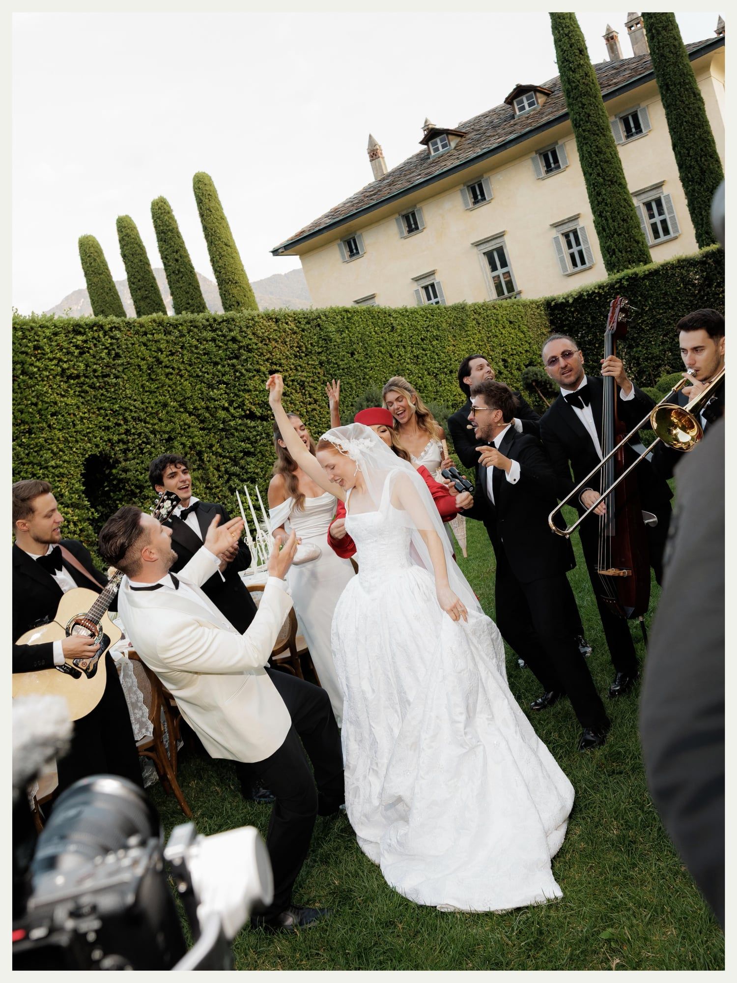 Bride, groom and guests dancing with a brass band in the garden at Villa Balbiano