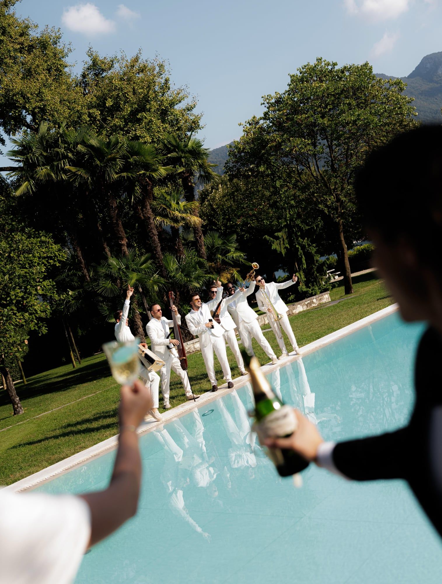 Guests raising champagne by the pool while a band plays at Villa Balbiano