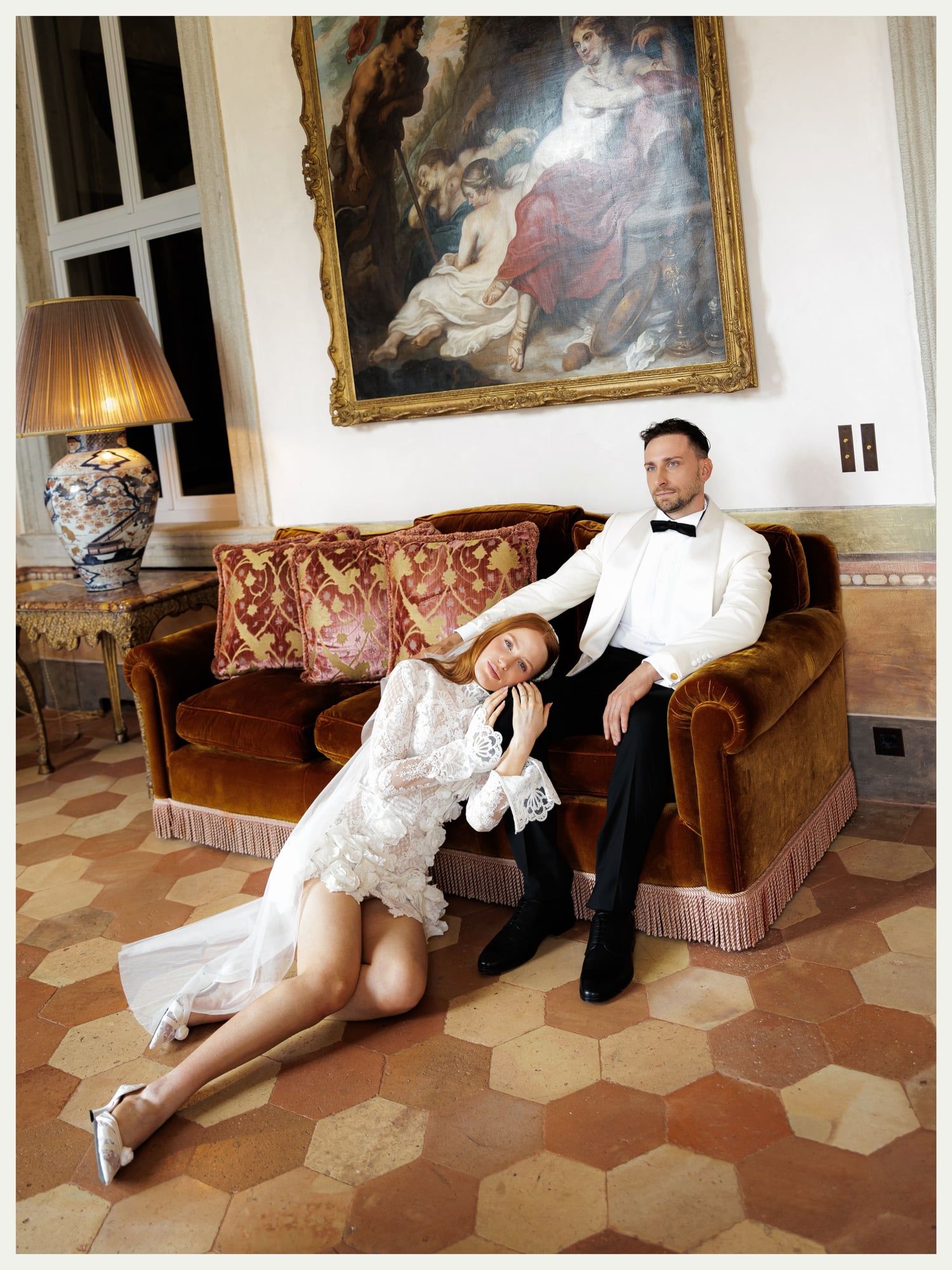 Bride and groom relaxing on a velvet sofa in a frescoed salon at Villa Balbiano