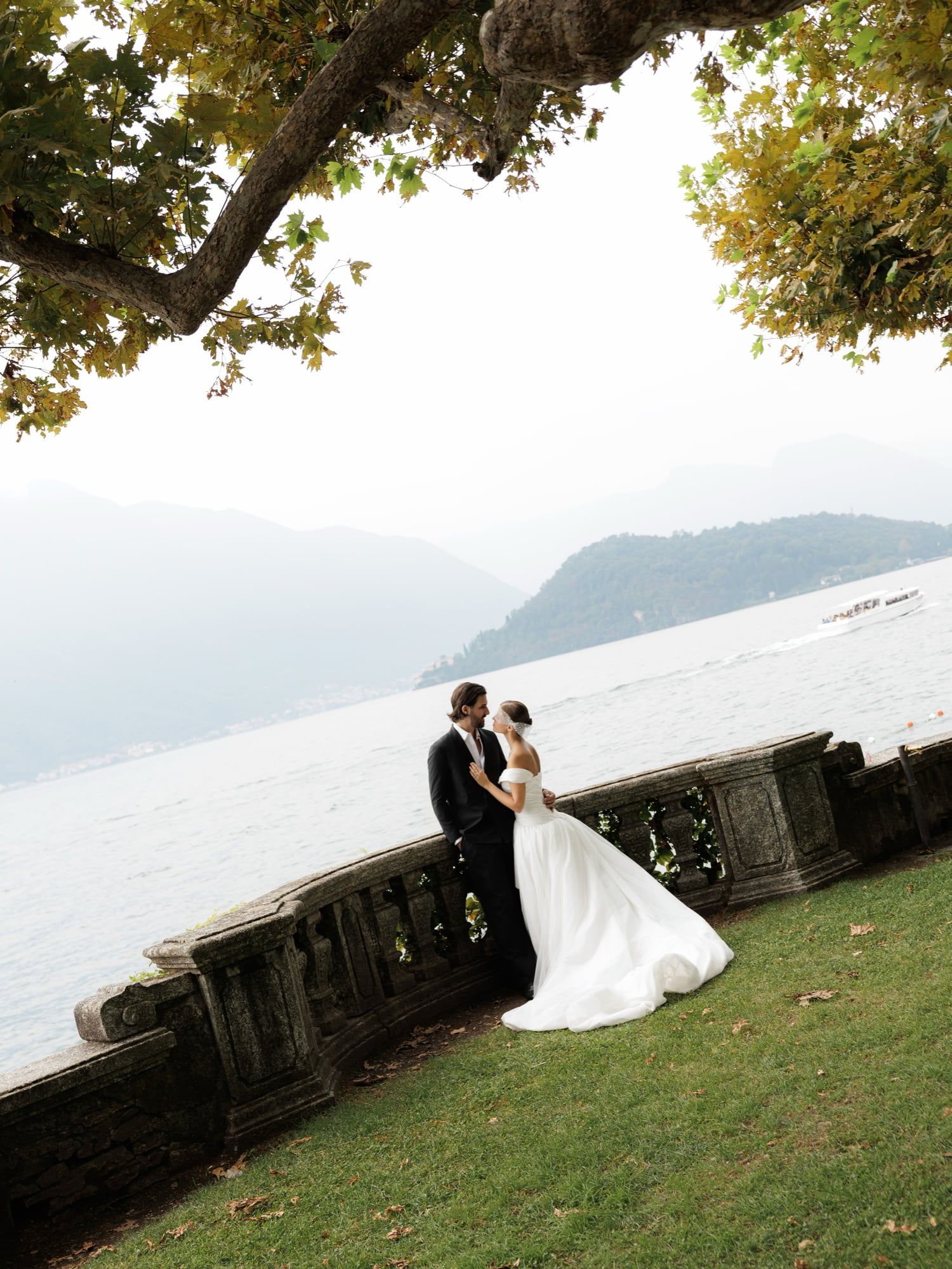 Bride and groom on a lakeside lawn under a tree, Lake Como