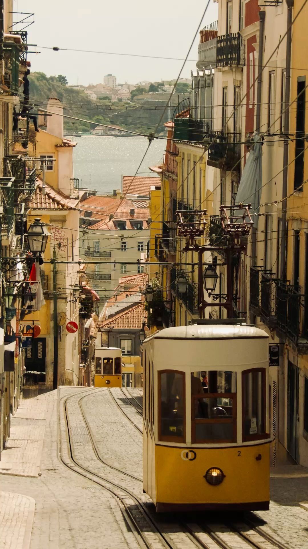Gelbe Straßenbahn in Lissabon auf einer steilen Straße mit alten Häusern