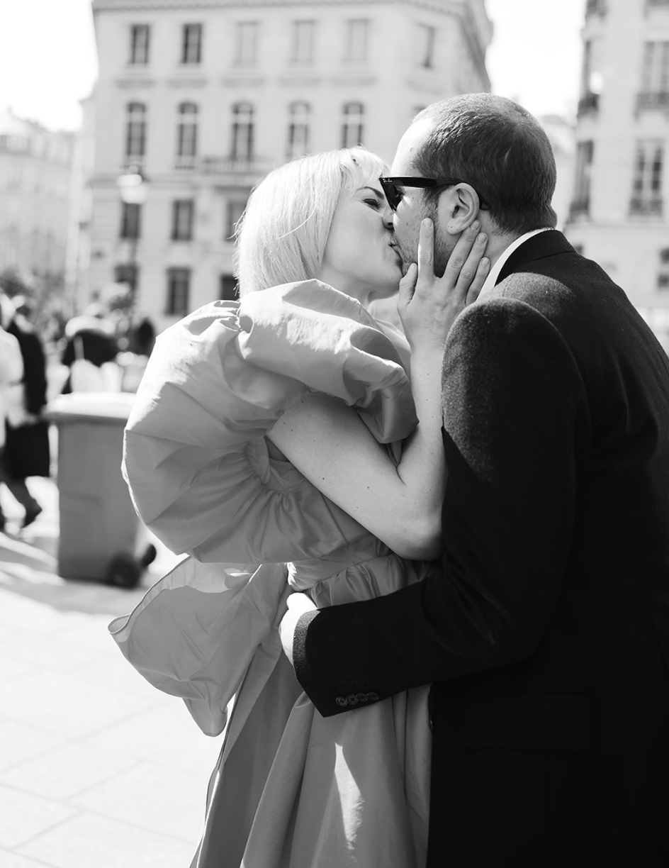 Foto en blanco y negro de una pareja besándose en una calle de París