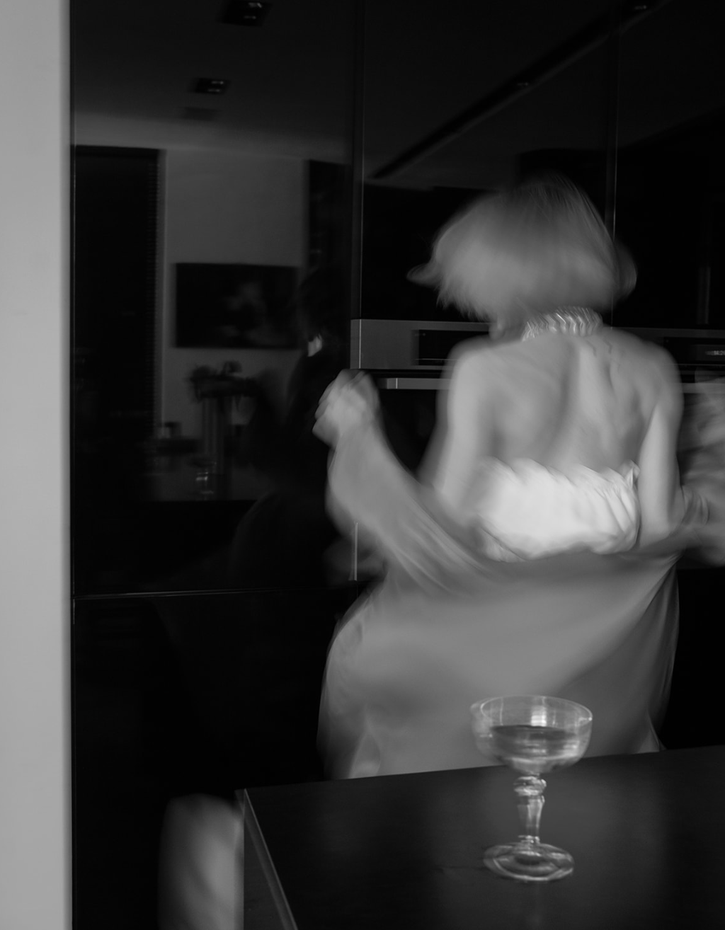 Foto en blanco y negro de una mujer girando en una habitación oscura