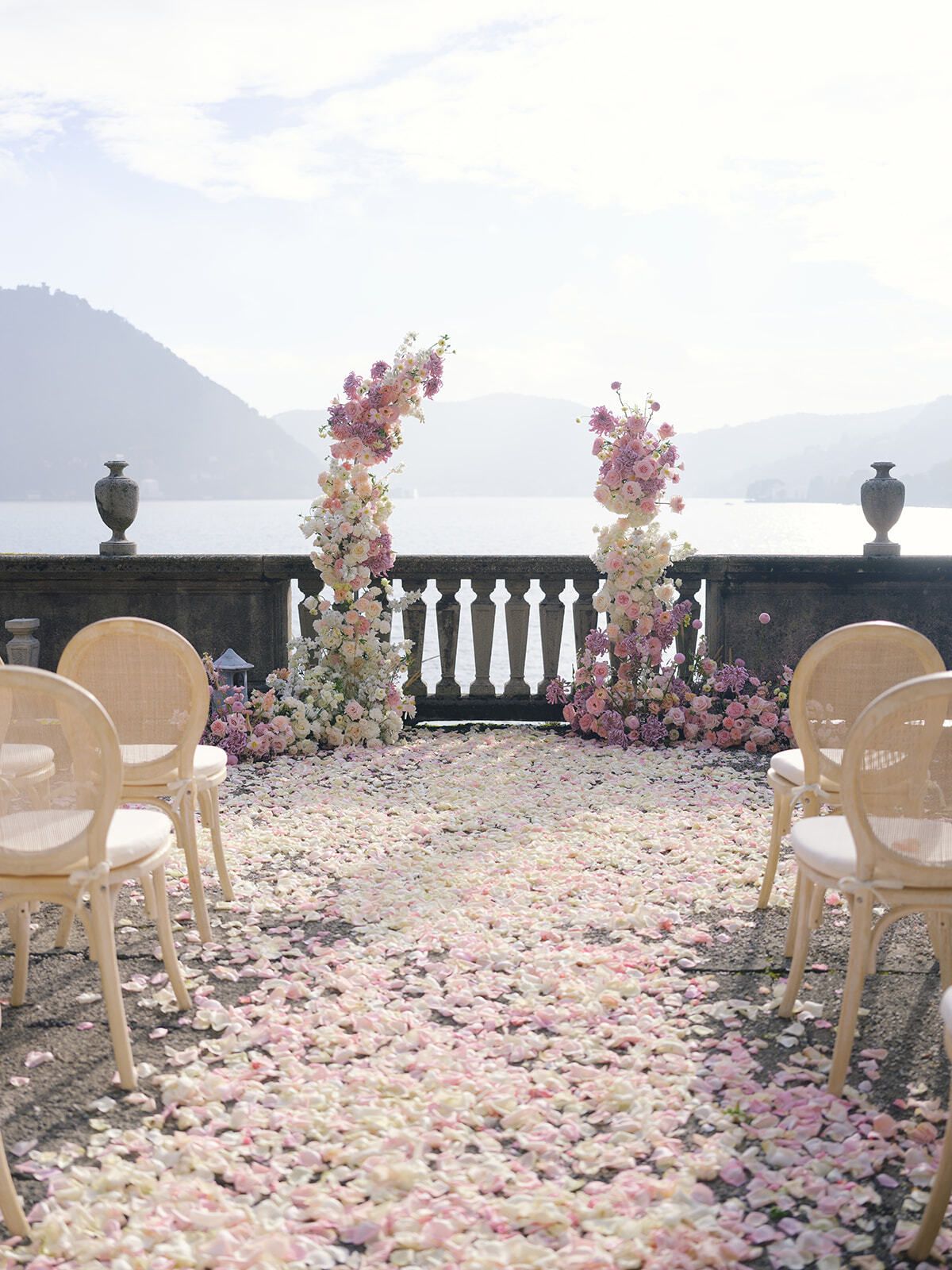 Pasillo de pétalos de rosa con arcos florales en la terraza de Villa Pizzo