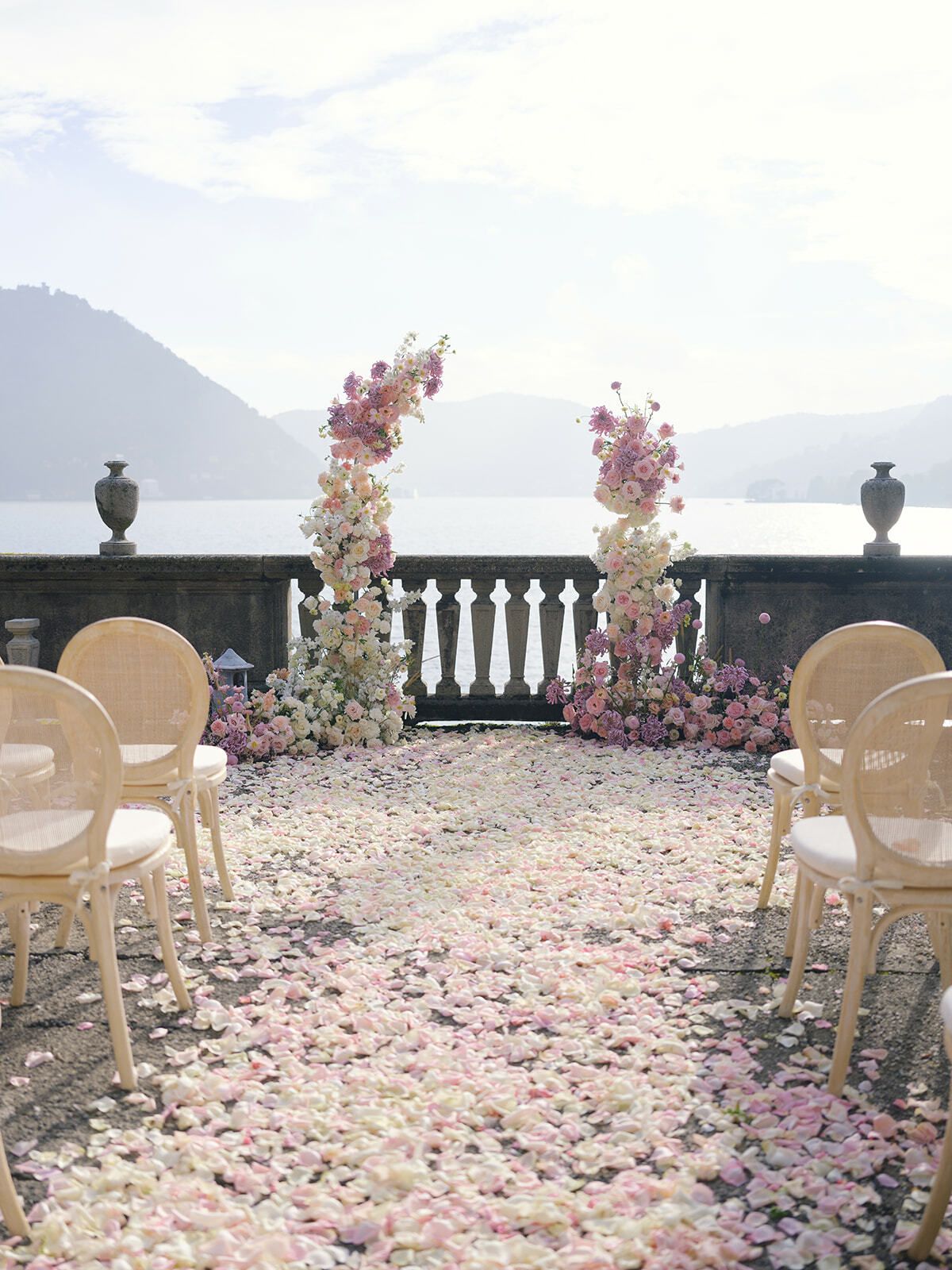 Pasillo de ceremonia de pétalos de rosa en la terraza del lago de Villa Pizzo