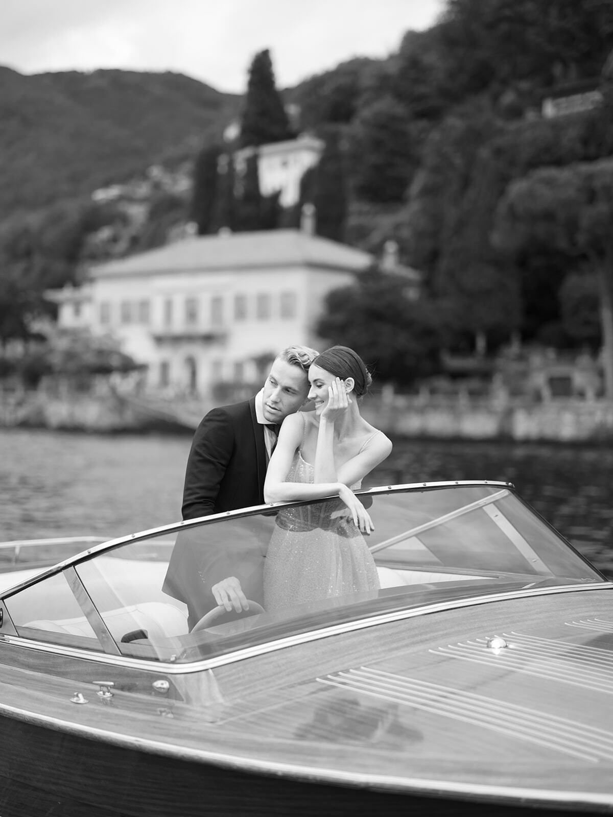 Foto en blanco y negro de una pareja en una lancha ante Villa Pizzo