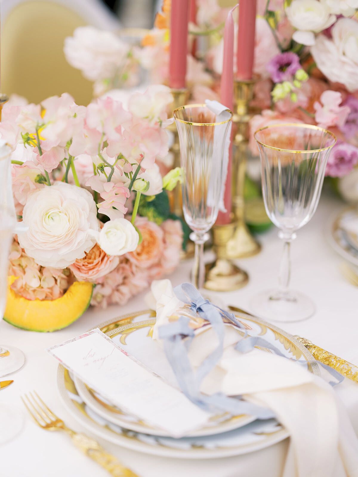 Gedeck mit rosa Blumen, goldenem Besteck und blauen Schleifen