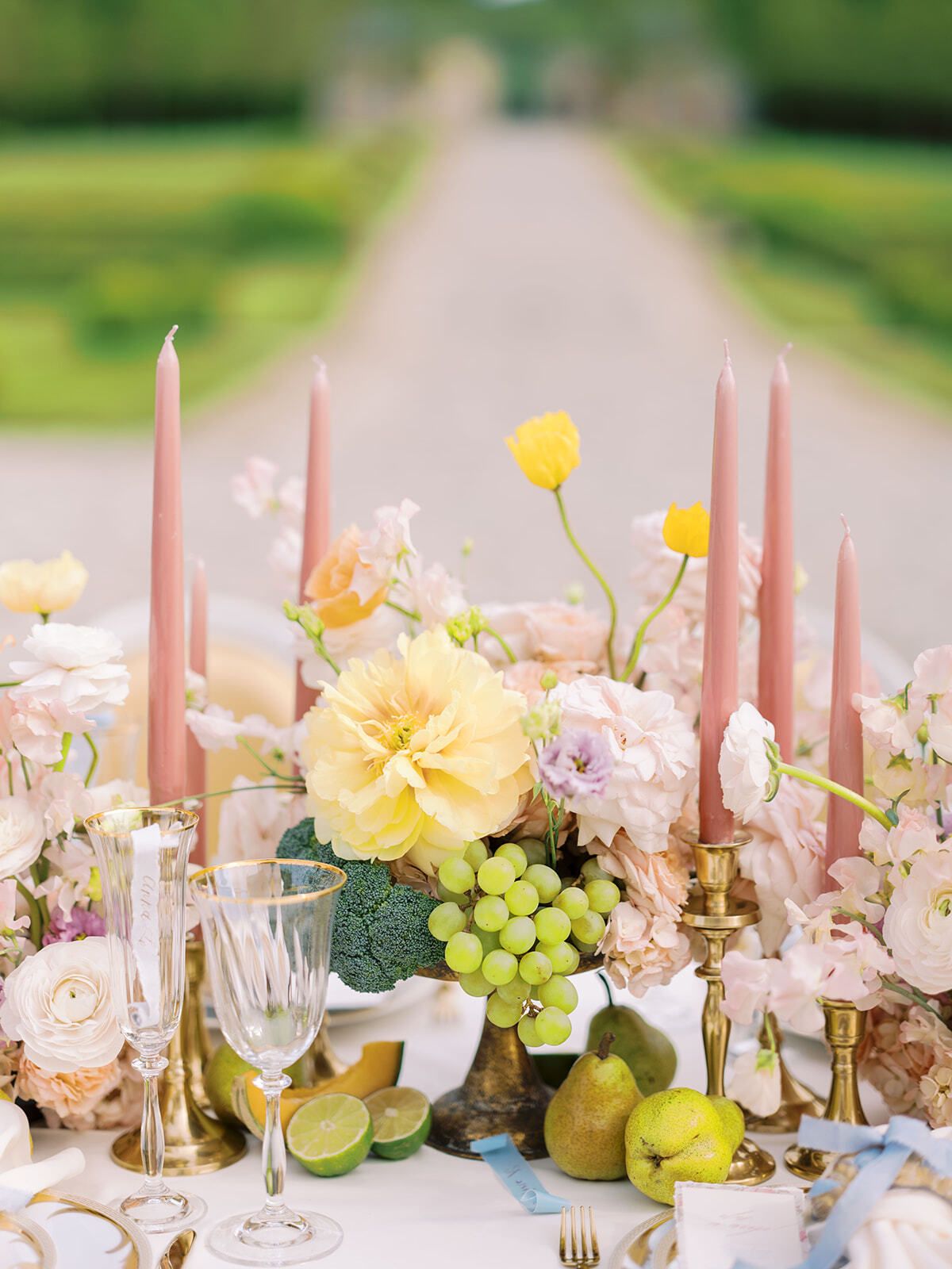 Tischdekoration mit rosa Kerzen, gelben Blumen und grünen Trauben