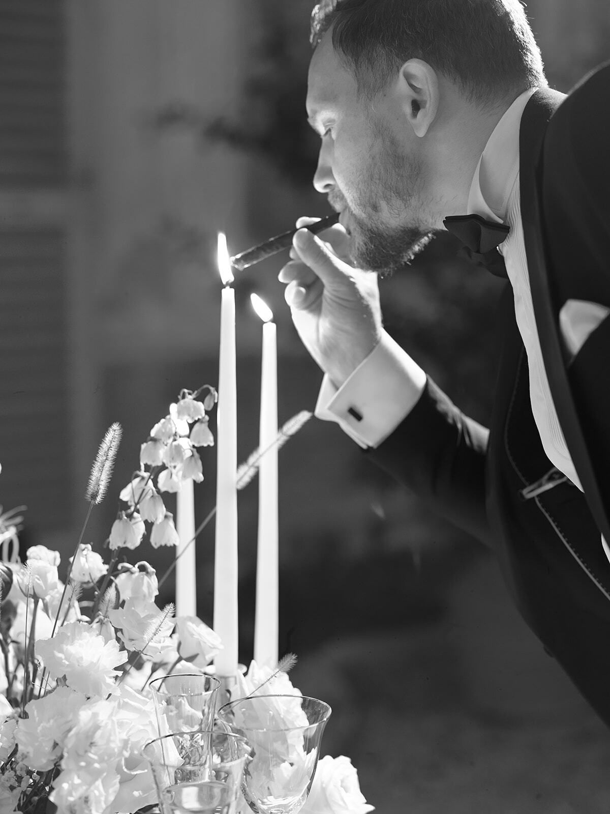 Foto en blanco y negro de un novio encendiendo velas
