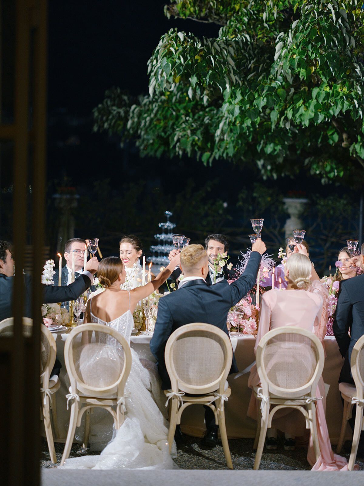 Invitados brindando en una recepción nocturna bajo los árboles, Villa Pizzo