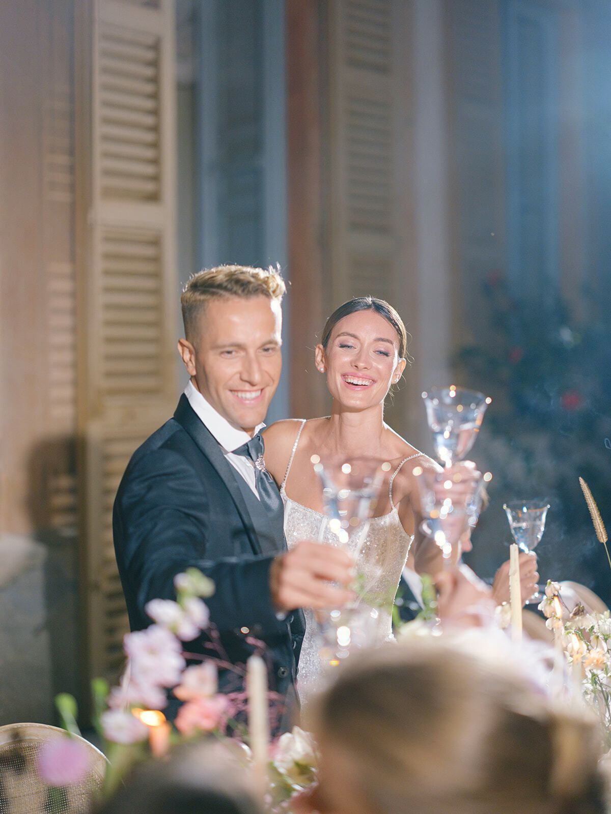 Novios sonriendo con champán durante la cena
