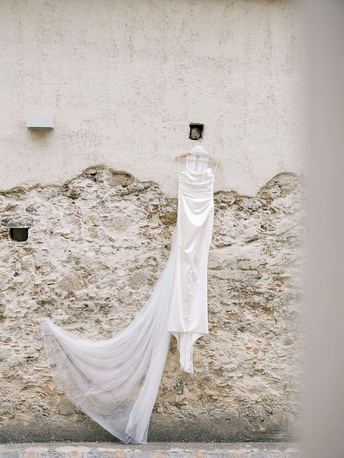 Brautkleid an einer alten Steinmauer