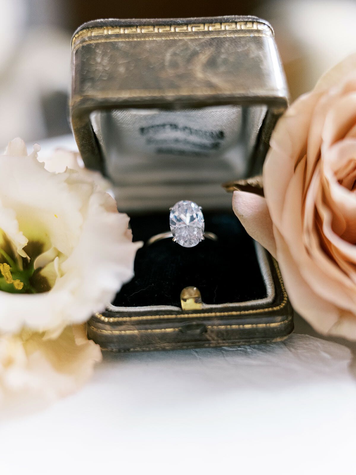 Ovaler Diamantring in einem antiken Ringkästchen mit Rosen