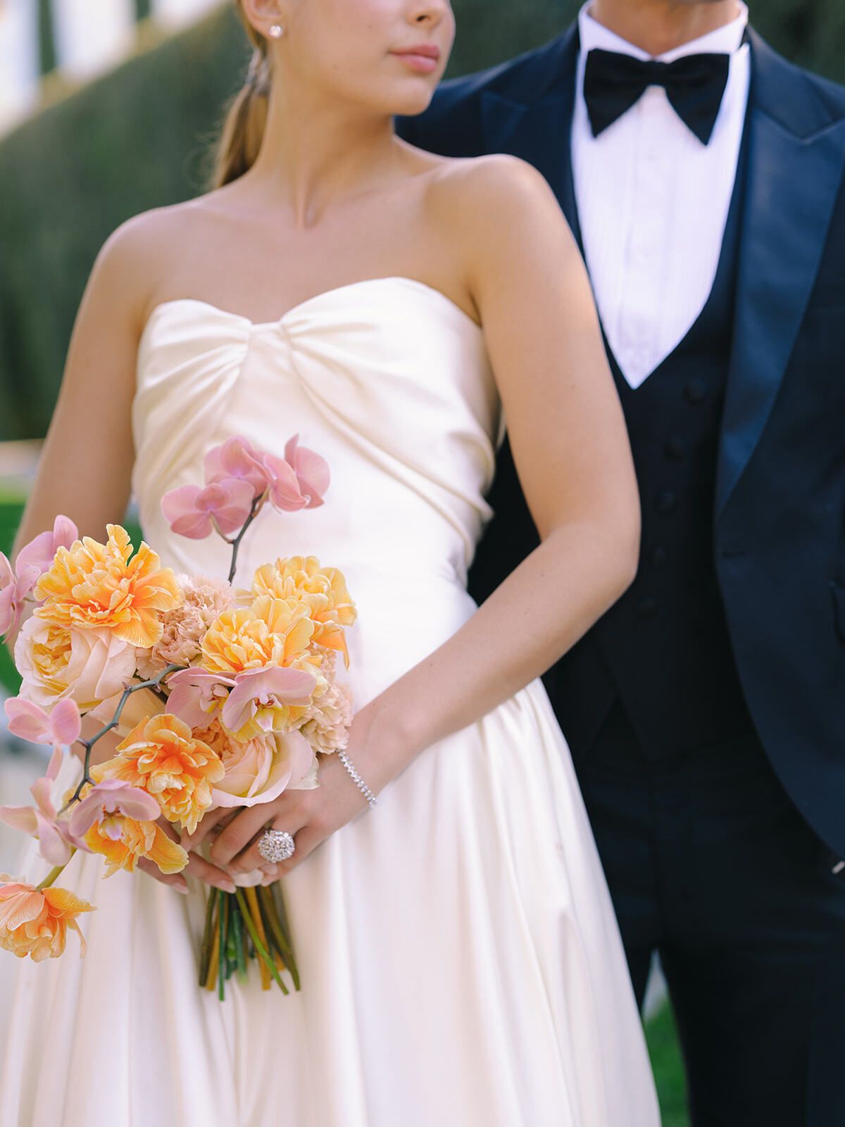 Braut im trägerlosen Kleid mit rosa-pfirsichfarbenem Strauß