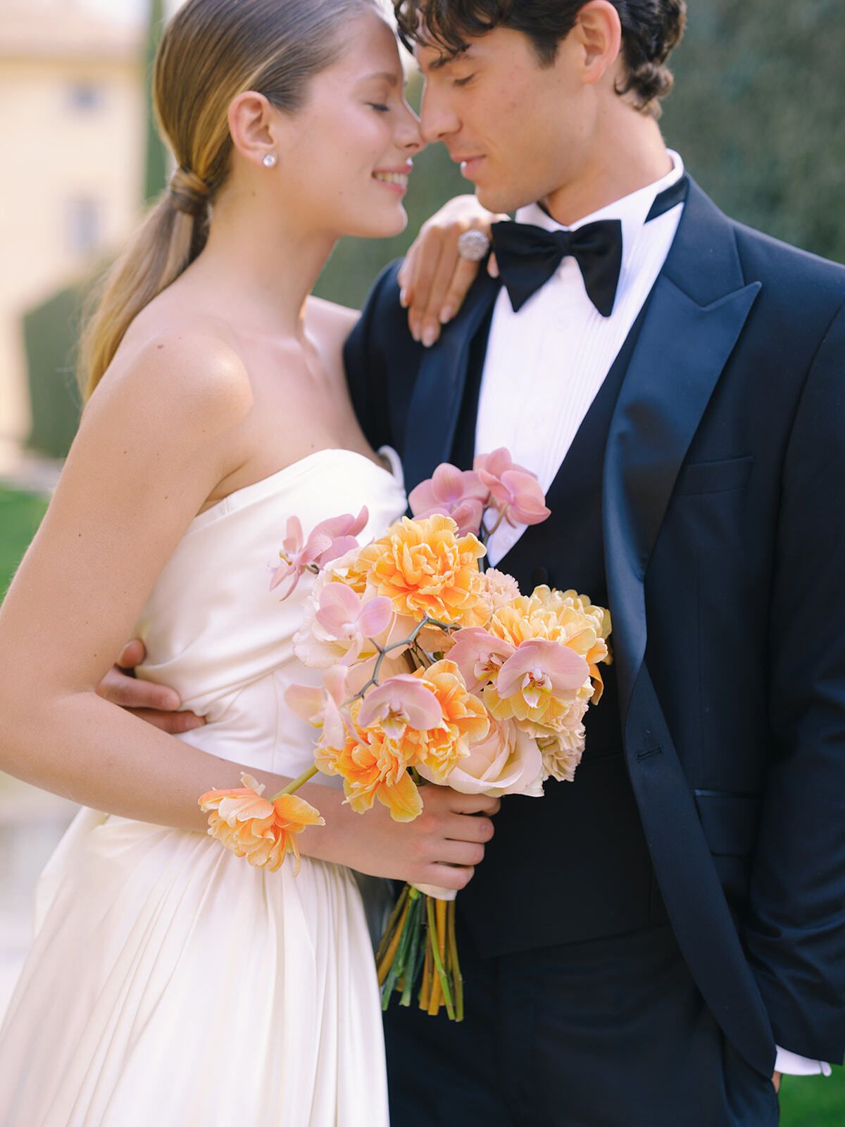 Sposi fronte contro fronte con un bouquet arancione e rosa