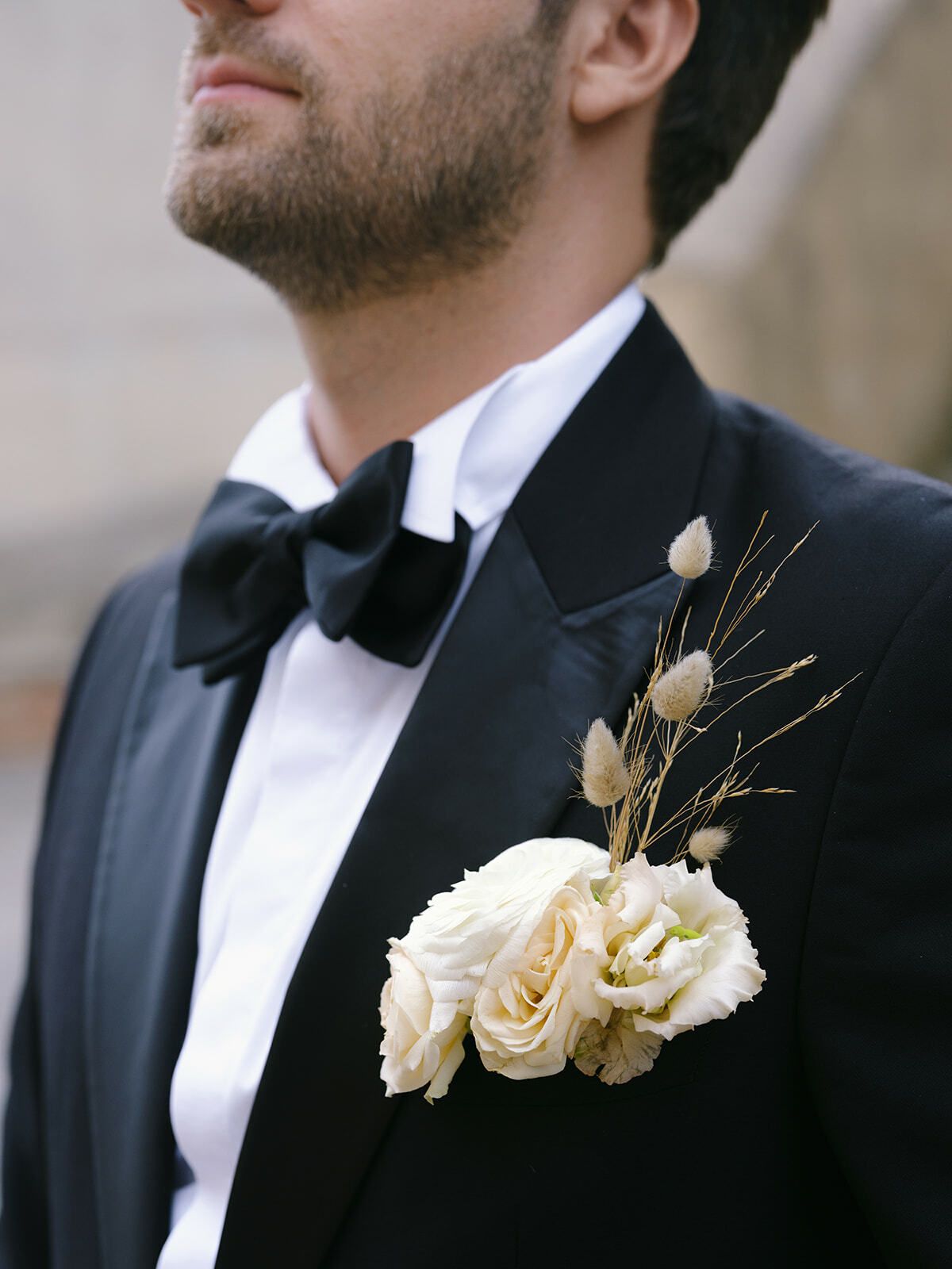 Anstecker des Bräutigams aus cremefarbenen Rosen am Smokingrevers