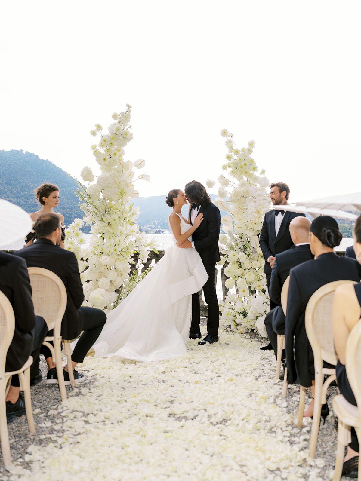 Couple kissing at the end of a petal aisle by Lake Como