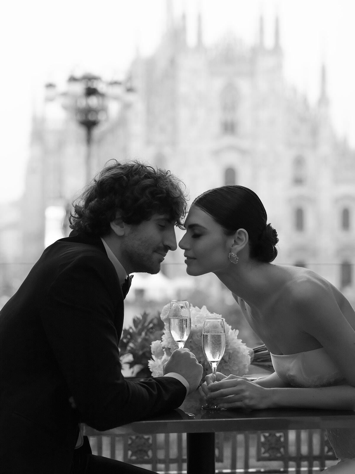 Foto en blanco y negro de una pareja en un café con el Duomo detrás