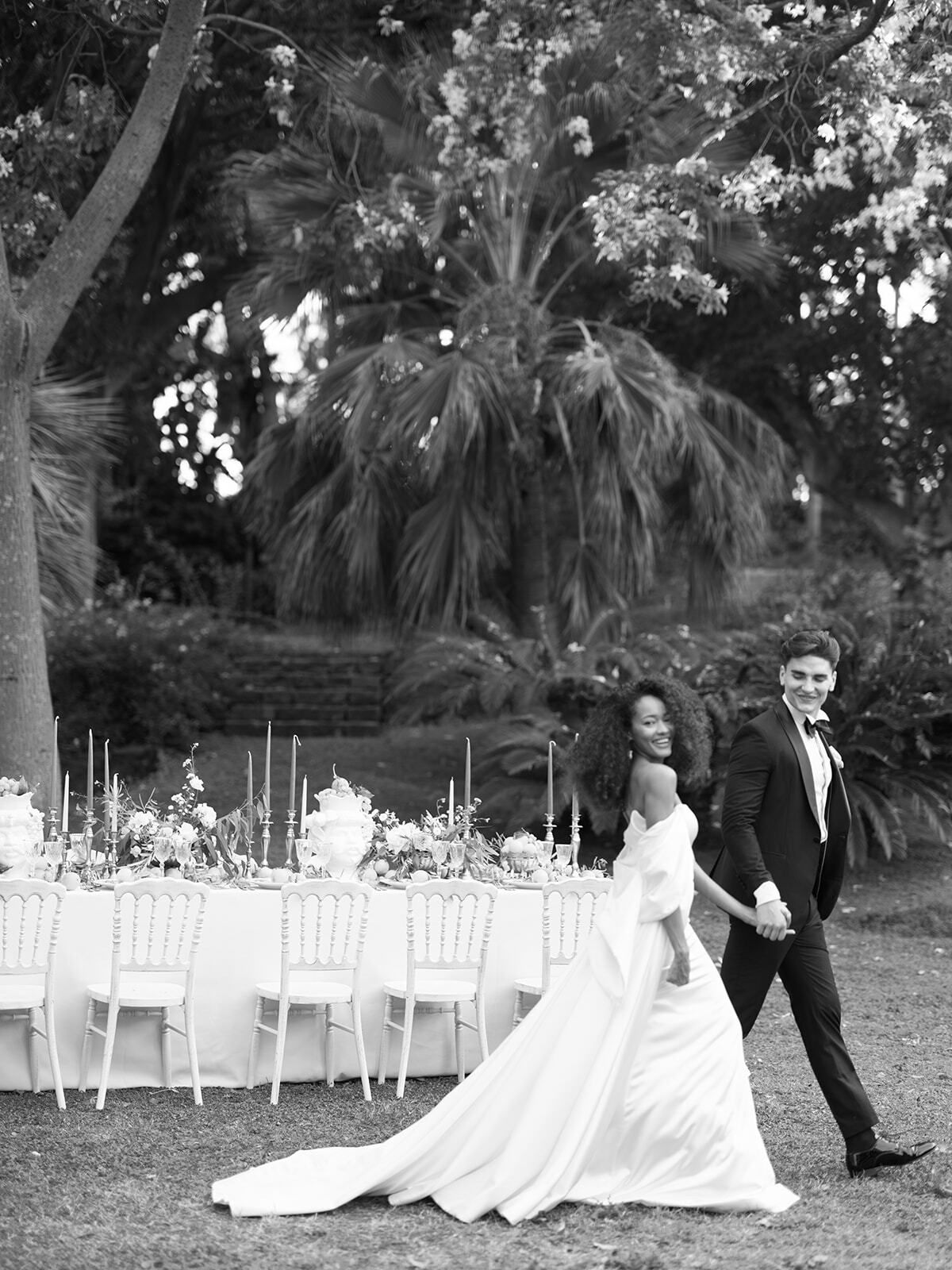 Schwarz-Weiß-Foto eines Paares, das an der Hochzeitstafel vorbeigeht