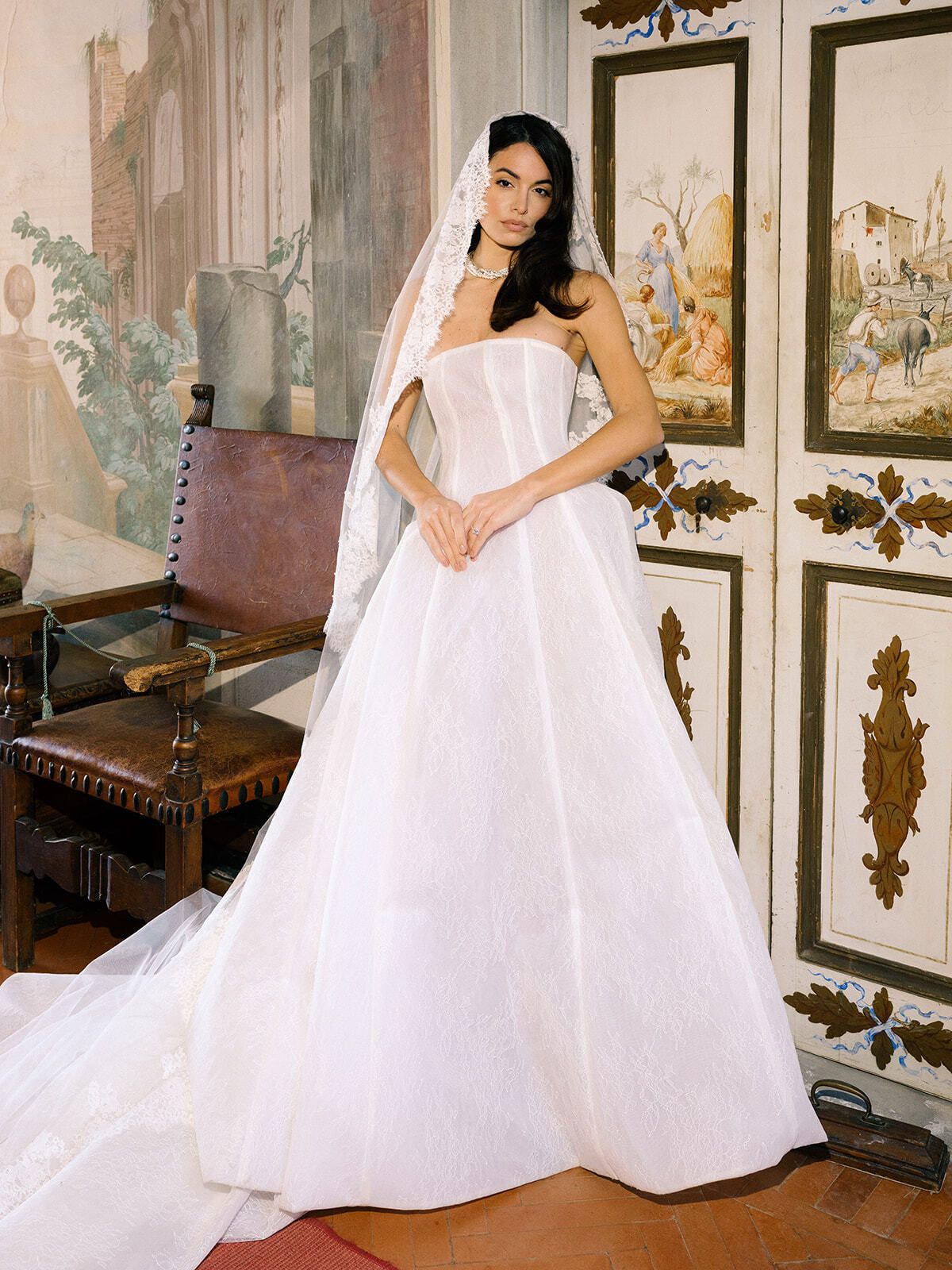Novia con vestido de larga cola entre muebles antiguos, Toscana