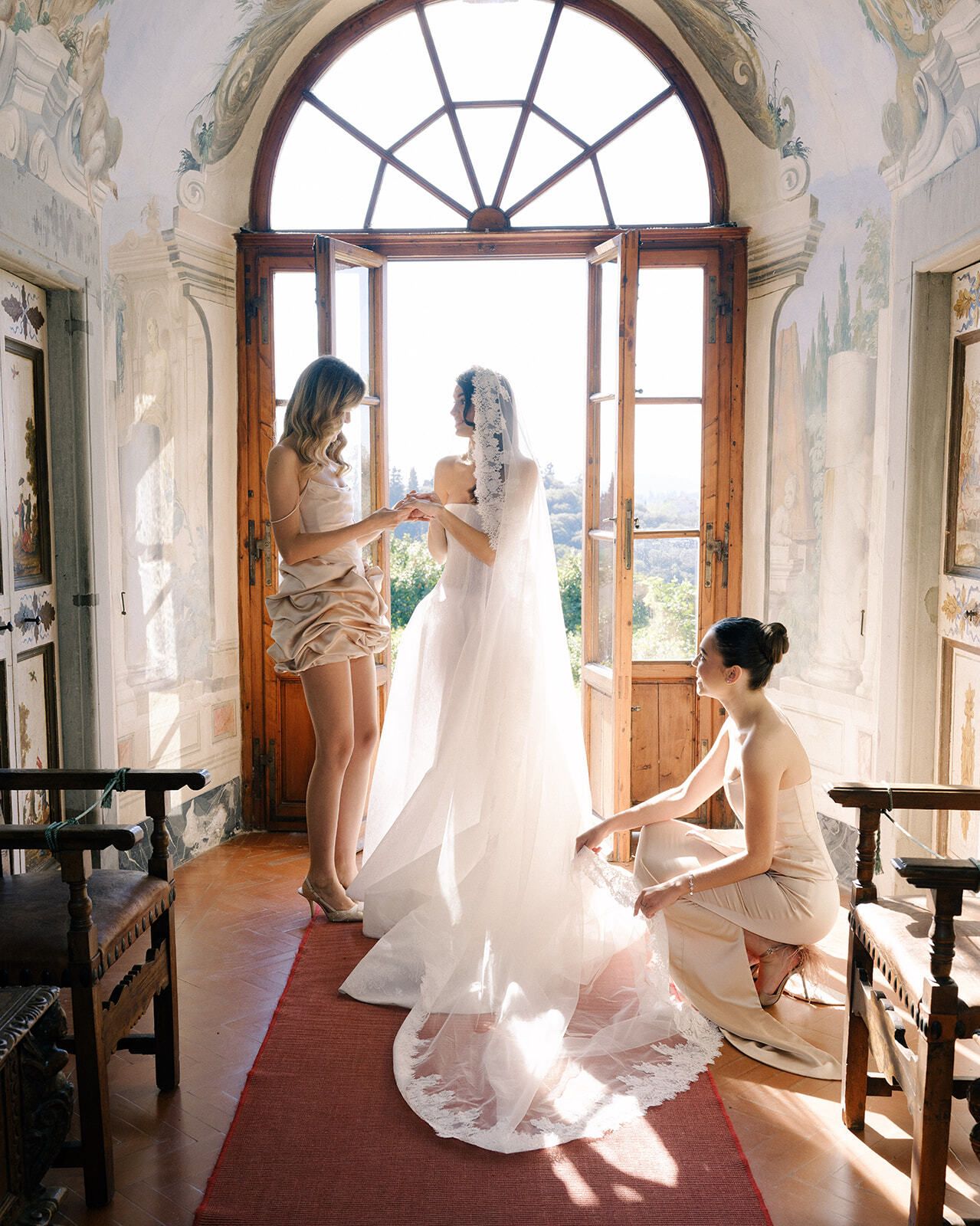 Novia y damas de honor en una ventana en arco de la villa